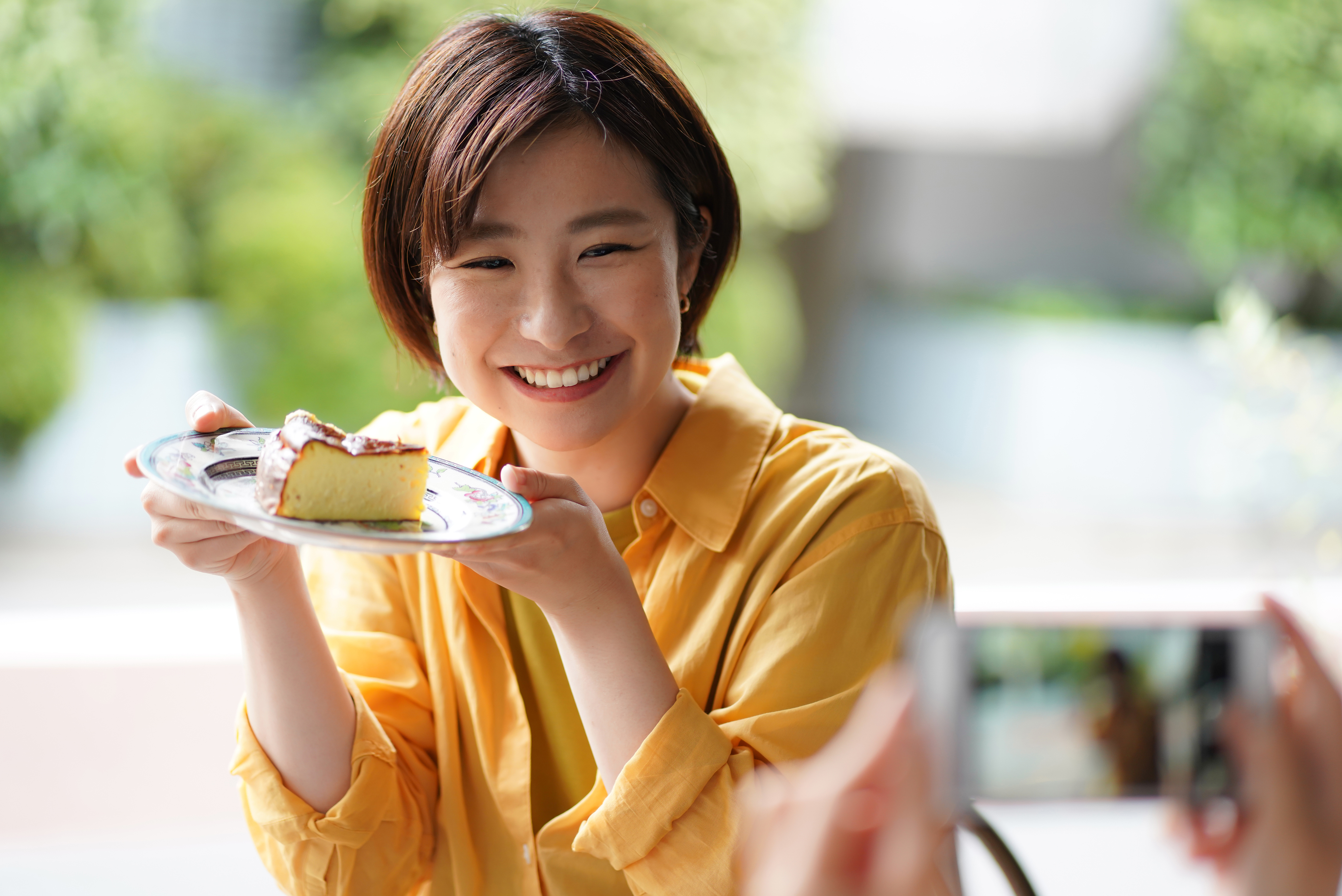 カフェで笑顔の女性がケーキを食べている画像